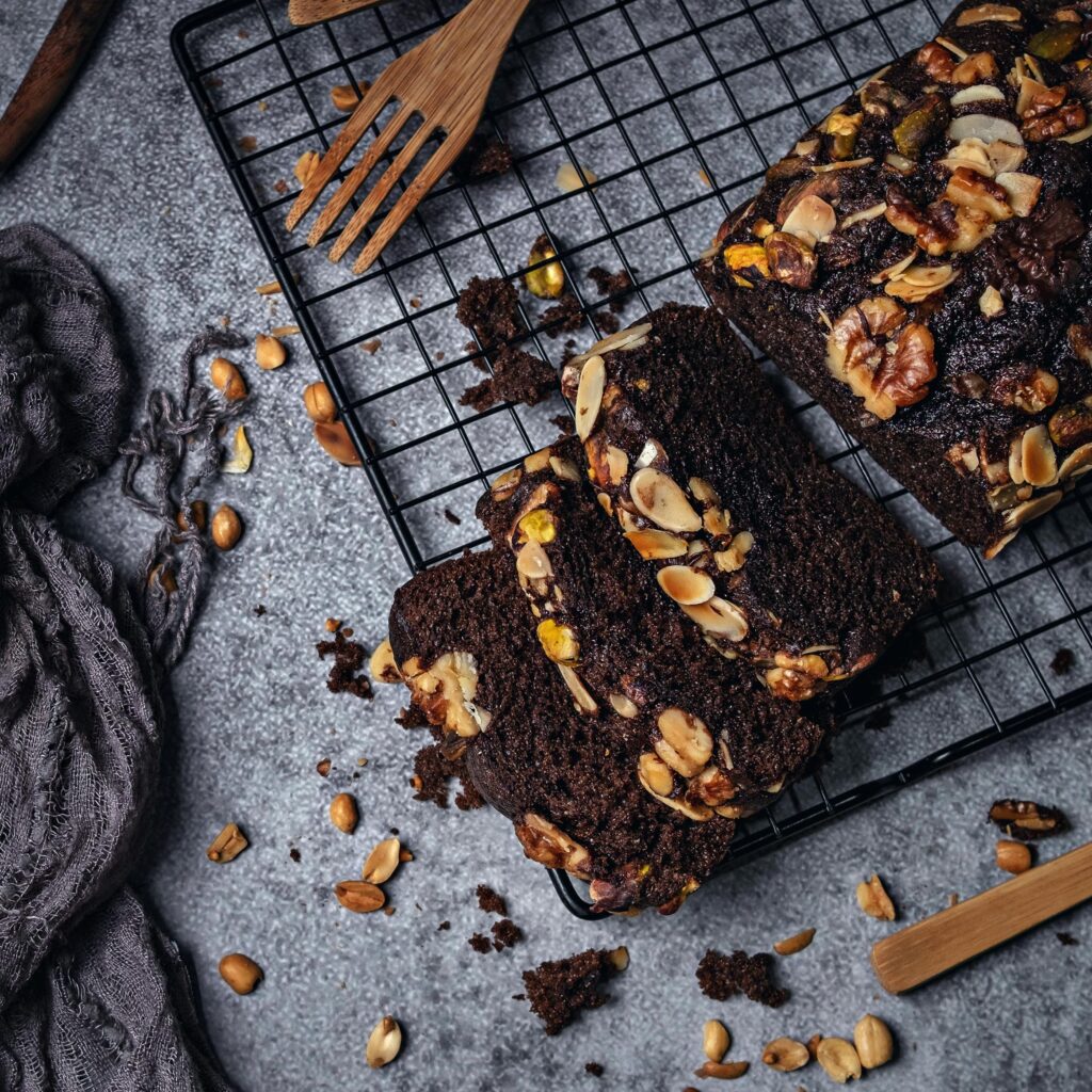 Sliced chocolate loaf cake with nuts on a wire rack, offering a delectable dessert option.